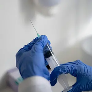 close up of gloved hands holding a syringe ready for via disc np