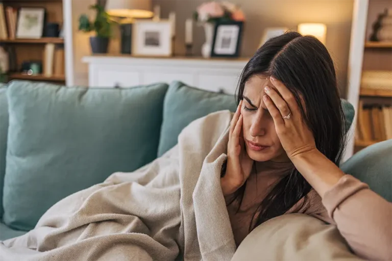 a young woman lying on the sofa in the living room with migraine