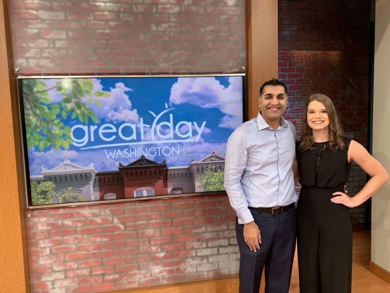Individuals stand in front of Great Day Washington news sign
