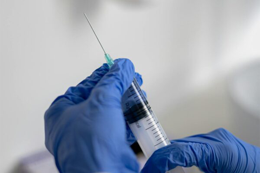 close up of gloved hands holding a syringe ready for via disc np