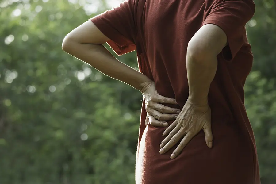 closeup hands of woman touching her back pain in nature background