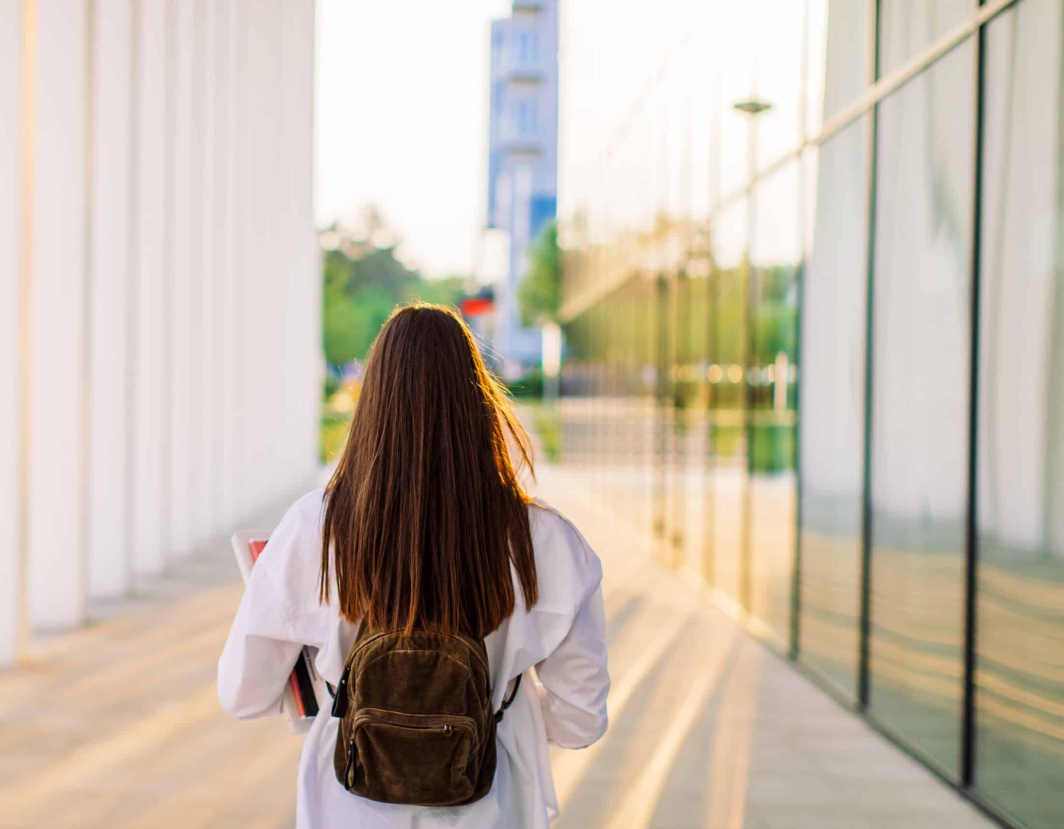 female student walking by university building