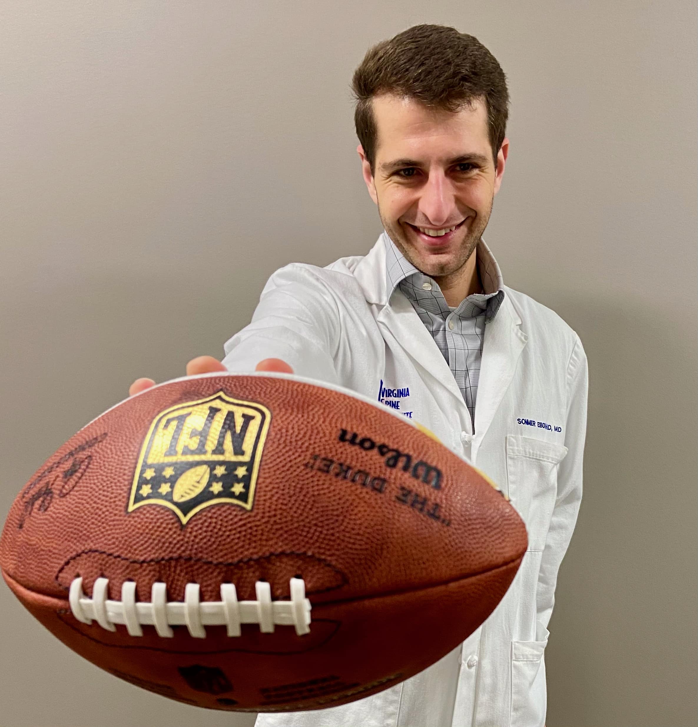 Doctor in white coat holding a football