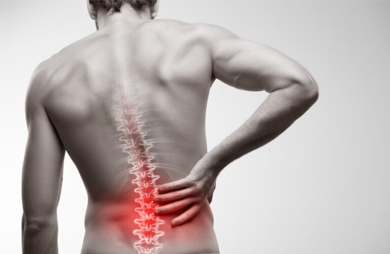 man gripping his lower spine in pain