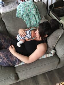 woman holding newborn laying down on couch