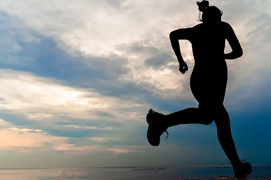 silhouette young woman jogging at beach during sunset